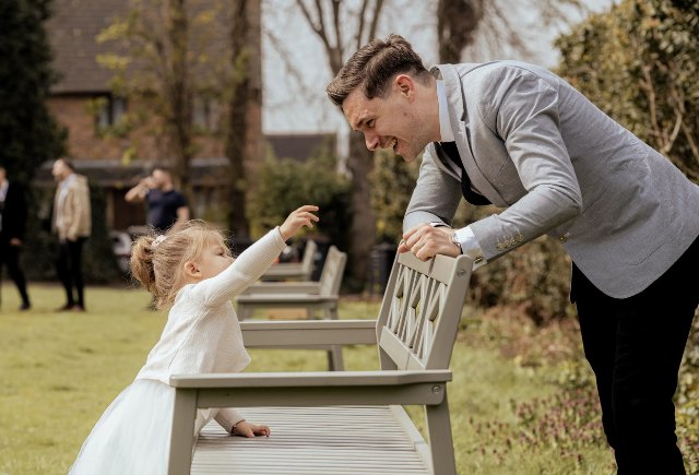 Flower girl reaching up to a guest