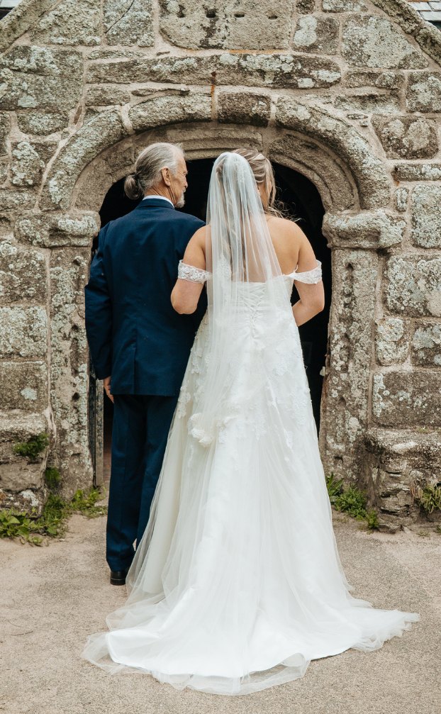 Father walking the bride into a stone church